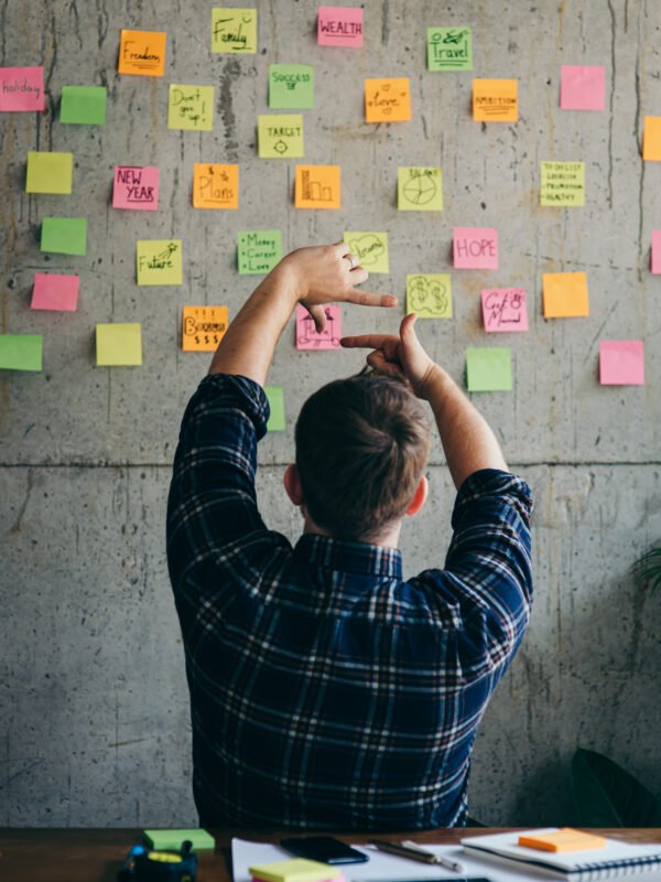 Back of entrepreneur sitting in office and look at colorful sticky notes